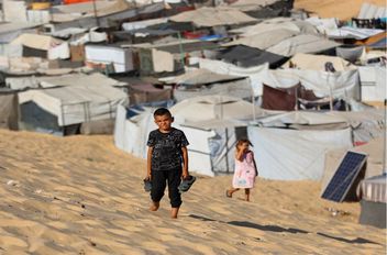 طفلان غزيان يقفان على أنقاض المأساة في غزة