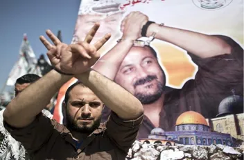صورة أرشيفية لفلسطيني يقف أمام صورة الأسير مروان البرغوثي