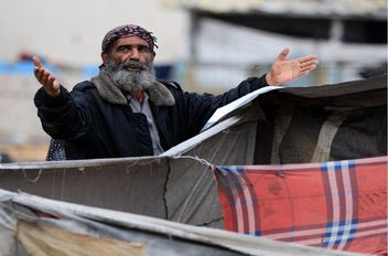 رجل فلسطيني يقف بجانب خيام في يوم ممطر