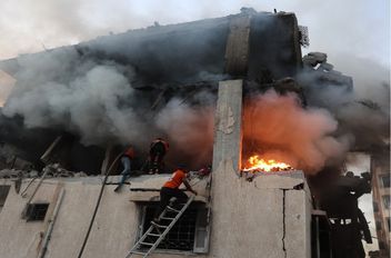 أفراد من الدفاع المدني يبحثون في منزل محترق استهدفه القصف الجوي الإسرائيلي في مدينة غزة