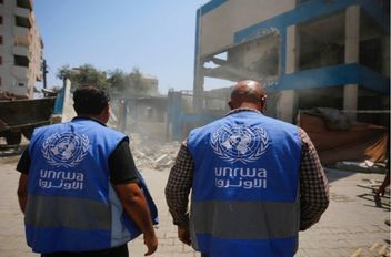 موظفو الأونروا بجوار مدرسة تابعة للوكالة متضررة في قطاع غزة