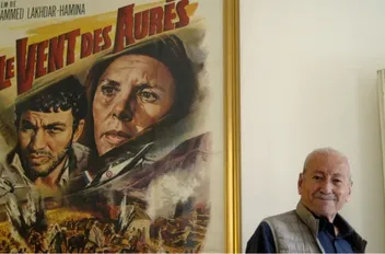 المخرج الراحل مع ملصق فيلم "ريح الأوراس"
