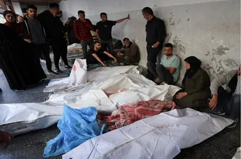 فلسطينيون بجوار جثامين شهداء في مستشفى الأهلي العربي المعمداني، في مدينة غزة