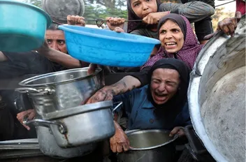 فلسطينيون ينتظرون دورهم لأخذ الطعام من مطبخ خيري في غزة