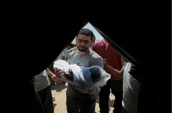 فلسطيني يحمل جثمان طفل شهيد في مدينة غزة