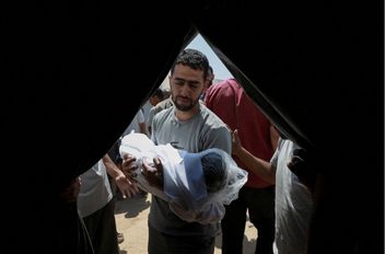 فلسطيني يحمل طفلا شهيدا في غارة إسرائيلية في قطاع غزة