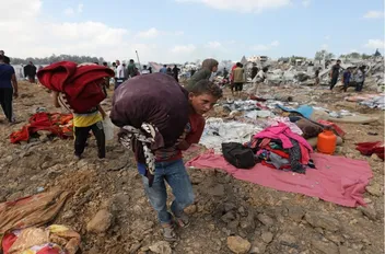 أطفال فلسطينيون يحملون أمتعتهم بعد غارة إسرائيلية على مخيم للنازحين