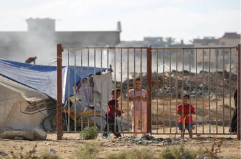 أطفال يقفون بجوار خيام في مخيم يؤوي فلسطينيين نازحين