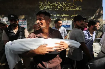 فلسطيني يحمل جثمان شهيد في مستشفى الشفاء في مدينة غزة