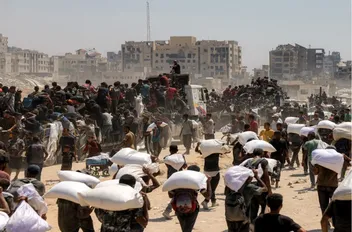 فلسطينيون يحملون أكياس طحين بعد دخول الشاحنات المحملة بالمساعدات الإنسانية إلى شمال غزة