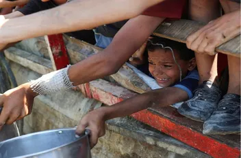أطفال فلسطينيون يتجمعون لتلقي الطعام، وسط قطاع غزة
