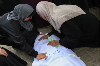 فلسطينيتان بالقرب من جثمان شهيد في