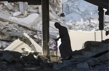 فلسطيني وسط أنقاض مبنى دمره قصف الاحتلال الإسرائيلي في قطاع غزة