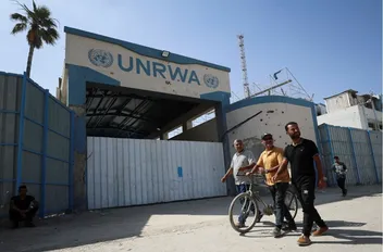 فلسطينيون يسيرون أمام مركز للأونروا في مدينة غزة
