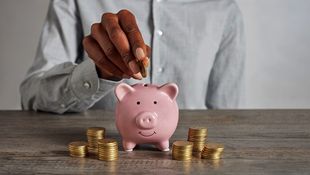 woman putting coin in piggy bank to save money