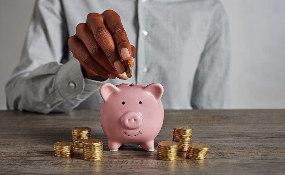 woman putting coin in piggy bank to save money